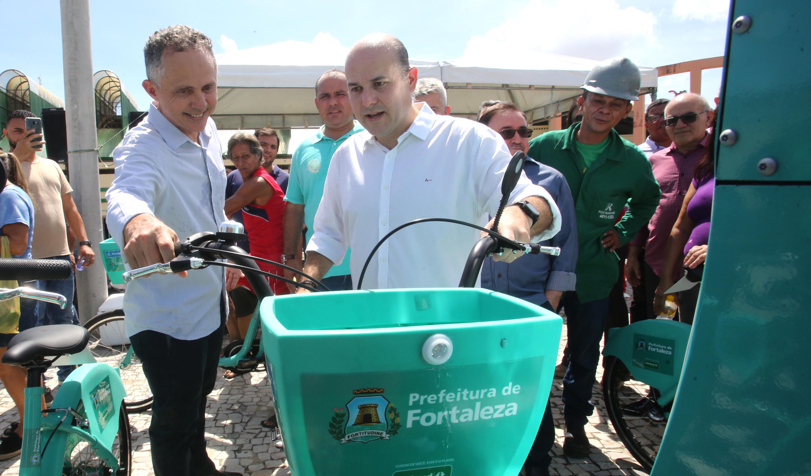 prefeito segurando guidão e olhando para bicicleta com pessoas atrás